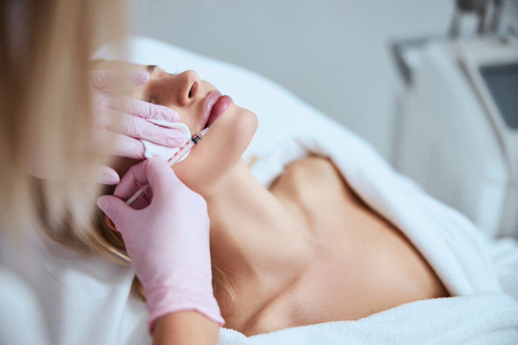 Female patient receiving a filler injection into her bottom lip